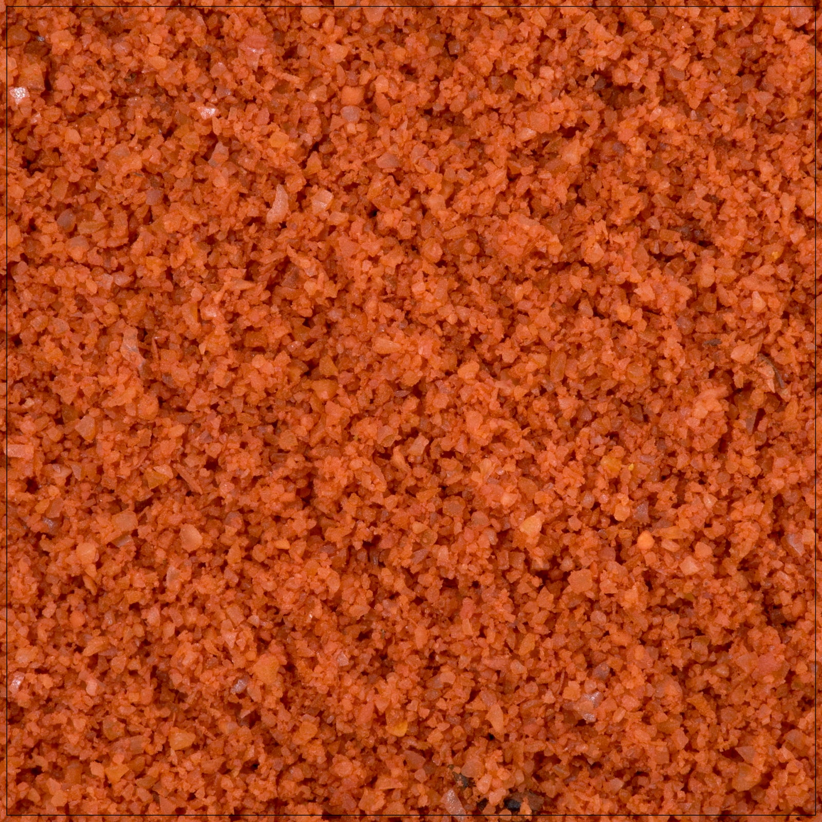 Close-up of vibrant orange Annatto Powder in a small glass jar.